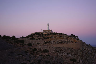 Low angle view of lighthouse by building against clear sky