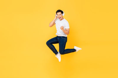Portrait of man jumping against yellow background