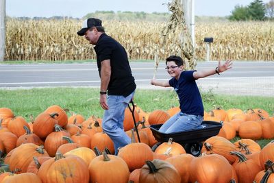 Full length of man standing by pumpkins on field