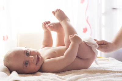 Portrait of shirtless baby lying on bed