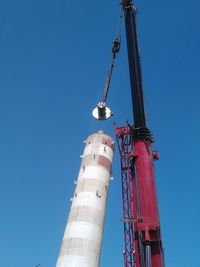 Low angle view of crane against clear blue sky