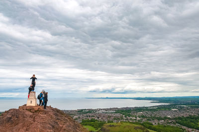 People standing on rock against sky