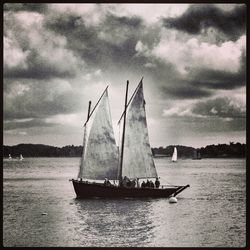 Boats in sea against cloudy sky