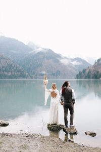 Happy newlyweds in love a man and a woman in wedding clothes embrace on the shore of the lake