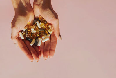 Cropped hand of person holding fruit against white background