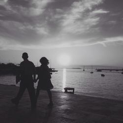 Silhouette friends standing on beach against sky