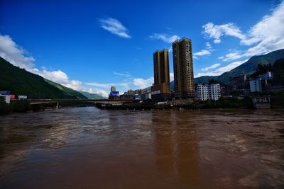 Scenic view of river by buildings against sky