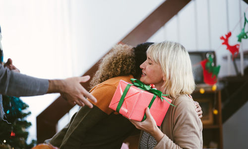 Man and woman giving gift to senior female at home