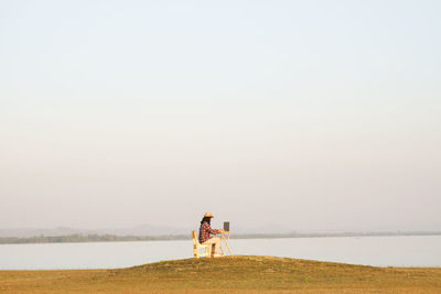 Woman by sea against clear sky