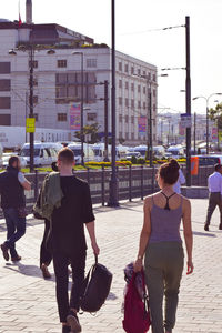 Rear view of people walking on street in city