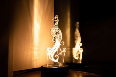 Illuminated lamp on table against wall