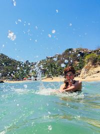 Young woman swimming in sea against sky