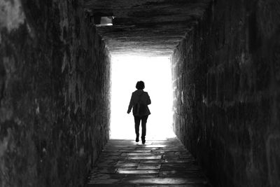 Rear view of man walking in tunnel