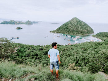 Rear view of man standing on mountain against sky