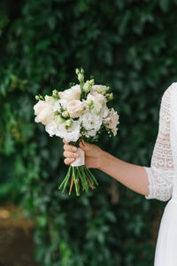 The bride holds a beautiful wedding bouquet of white flowers in her hands
