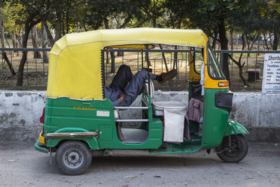 Low section of man resting in rickshaw against park