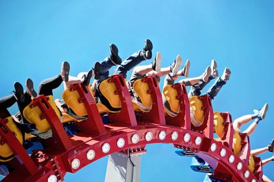 Low angle view of amusement park ride against clear blue sky