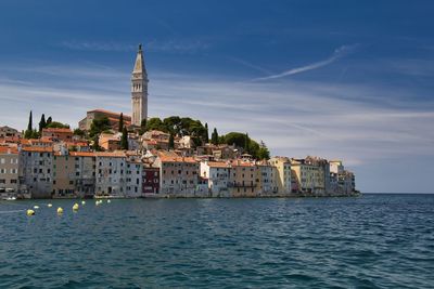 View of buildings by sea against sky in city