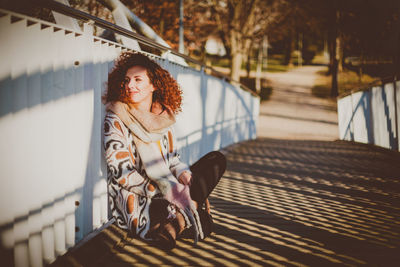 Portrait of young woman walking on railing