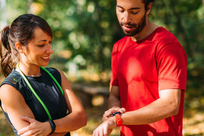 Young couple checking progress on their smart watches after outdoor training