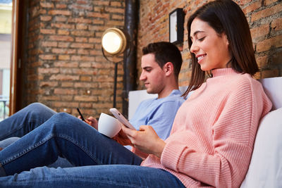 Young couple looking at mobile phone while lying on bed at home