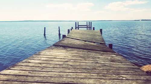 Wooden pier over sea against sky