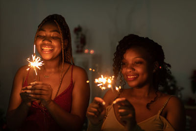 Portrait of woman holding illuminated string lights at home