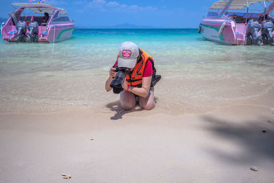 Full length portrait of woman sitting on beach