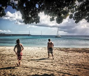 Rear view of men walking on beach