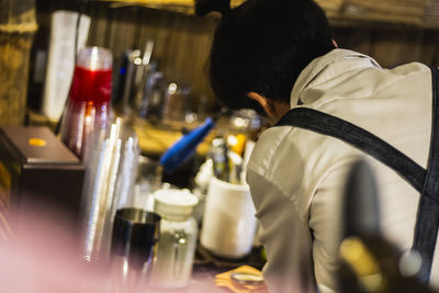 Rear view of man working on glass at restaurant