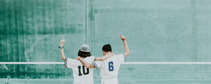 Rear view of people showing middle fingers wile standing at playground