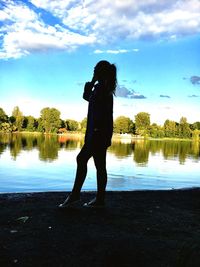 Silhouette woman standing by lake against sky