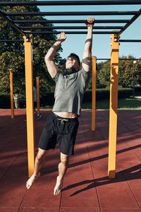 Young man bodybuilder exercising on monkey bars during his workout in a calisthenics park