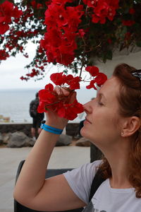 Woman smelling red flower in city