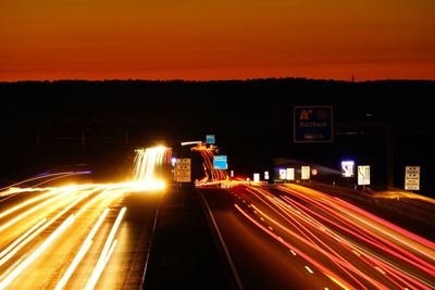 Light trails on road against sky at night