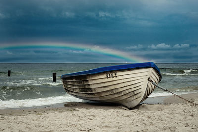 Boat moored on beach against sky