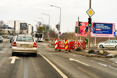 Road sign on street in city against sky