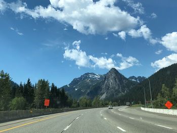 Road by mountains against sky