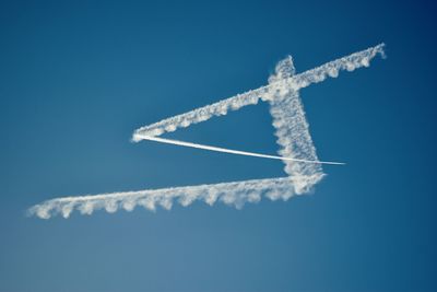 Low angle view of airplane flying against blue sky