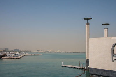 Buildings by sea against clear sky