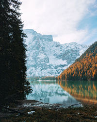 Scenic view of lake by snowcapped mountains against sky in autumn, lake braies