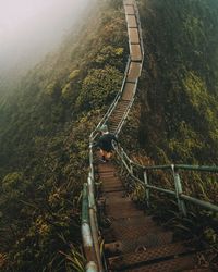 High angle view of man walking on steps amidst mountains at forest
