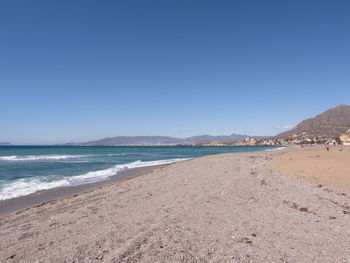 Scenic view of beach against clear blue sky