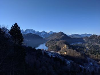 Scenic view of lake and mountains against clear blue sky