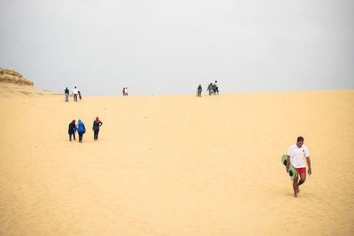 People walking at desert against sky