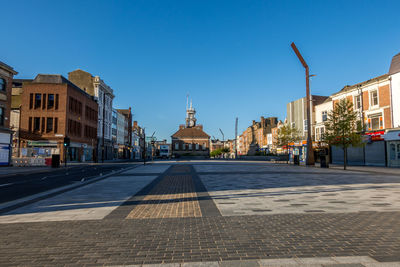 Street amidst buildings against clear blue sky