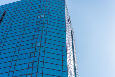 Low angle view of glass building against clear blue sky