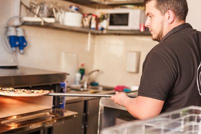 Side view of man preparing food in kitchen