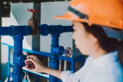 Side view of engineer wearing hardhat adjusting metallic valve