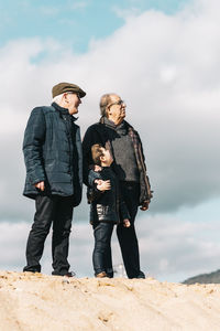 Men standing on rock against sky